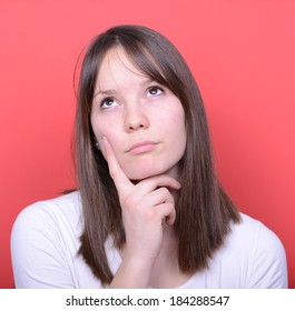 Portrait of beautiful girl looking above and thinking against red background