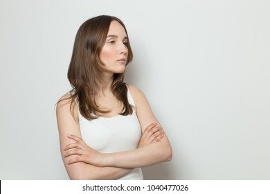 Portrait Of A Beautiful Girl On A White Background. Young Serious Woman Looking Away On A White Background. Free Place