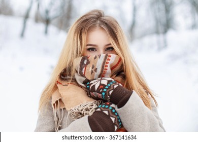 Portrait of a beautiful girl in a scarf and gloves in winter park. Vintage collection. Keep warm