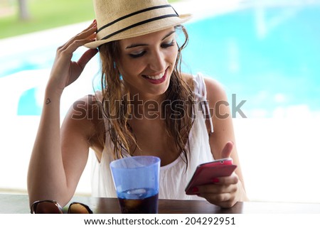 Portrait of beautiful girl taking a mobile phone at the swimming pool.