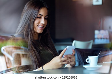 Portrait Of Beautiful Girl Using Her Mobile Phone In Cafe.