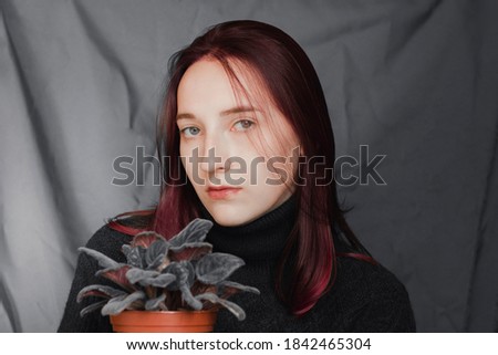 Portrait of a beautiful girl with a violet. The girl has purple hair and a violet.