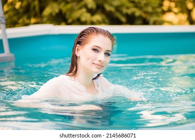 Portrait Of A Beautiful Girl With Wet Hair Floating In The Pool, Wearing A White Shirt. Rest In The Water In Hot Weather.
