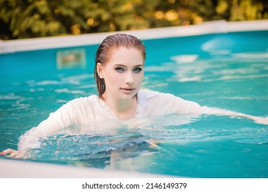 Portrait Of A Beautiful Girl With Wet Hair Floating In The Pool, Wearing A White Shirt. Rest In The Water In Hot Weather.
