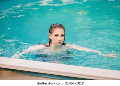 Portrait Of A Beautiful Girl With Wet Hair Floating In The Pool, Wearing A White Shirt. Rest In The Water In Hot Weather.
