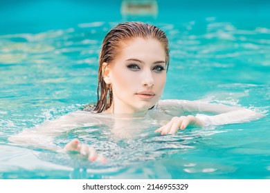 Portrait Of A Beautiful Girl With Wet Hair Floating In The Pool, Wearing A White Shirt. Rest In The Water In Hot Weather.
