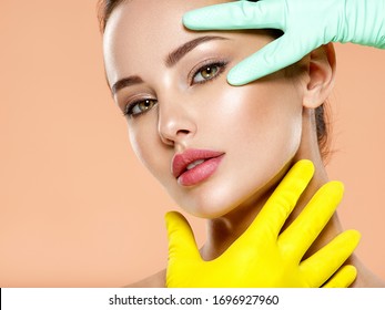 Portrait of beautiful  girl which touching her fresh face. Face skin check before plastic surgery. Beautician touching woman face. Doctor checks a skin before plastic surgery. Beauty treatments.