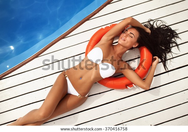 プールの横にある白い水着を着た美しい女の子のポートレート トップビュー の写真素材 今すぐ編集