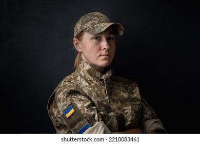 Portrait of beautiful girl with yellow and blue Ukrainian flag on her cheek wearing military uniform. Ukrainian women in the army. Black background. Stand with Ukraine