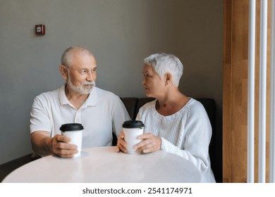 Portrait of beautiful gray-haired senior couple enjoying cozy coffee date in cozy cafe, cherishing each other company with heartfelt conversation and warm beverages. Concept of active aging. - Powered by Shutterstock