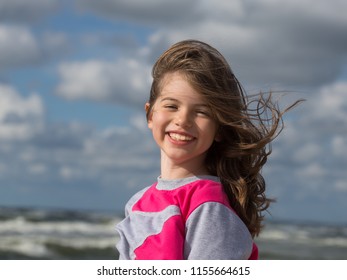 Portrait of a beautiful happy girl flipping hair on the beach