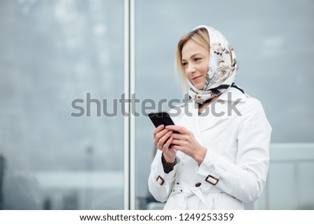 Portrait of beautiful and happy girl using smart phone in the city. Young woman in a big city  using phone with copy space.