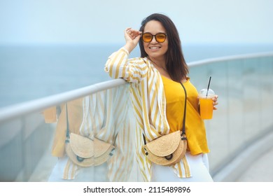 Portrait Of Beautiful And Happy Milenniall Woman 30-35 Years Old On Vacation Enjoy The View. Smiling Overweight Female In Fashion Clothes And Sunglasses Drinking Takeaway Juicy Coctail In Summer Day