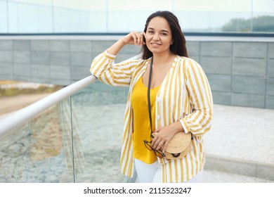 Portrait Of Beautiful Happy Plus Size Woman 30-35 Years Old On Vacation Enjoy The View. Smiling Overweight Female In Fashion Clothes And Sunglasses In Yellow Colors Drinks Juicy Coctail In Summer Day