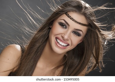 Portrait of beautiful happy smiling woman with blowing brown long silky hair. Make-up, perfect skin. Hair health, hairstyle, hair care.