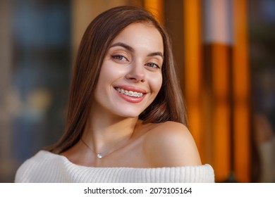 portrait of a beautiful happy smiling young woman with braces. Attractive girl with bracket system posing in city outdoor. Brace, bracket, dental care, malocclusion, orthodontic health concept. Blurre