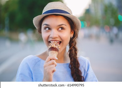 Portrait of beautiful happy white Caucasian brunette girl woman with dimples on cheeks and tanned skin in blue dress and hat eating ice-cream cone, sunset on summer day, lifestyle - Powered by Shutterstock