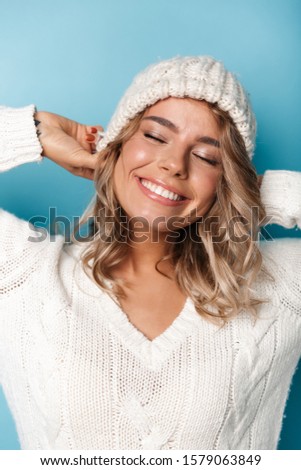 Portrait of beautiful happy woman in white hat smiling with eyes closed isolated over blue background