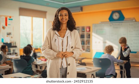 Portrait of a Beautiful Happy Young Teacher Standing in Classroom with Crossed Arms, Looking at Camera and Smiling. Multiethnic Female Working in Elementary School, Taking Care of Talented Children - Powered by Shutterstock