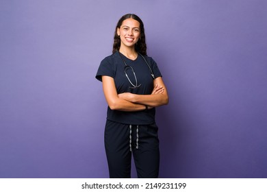 Portrait Of A Beautiful Hispanic Doctor Smiling And Looking At The Camera While Standing In Front Of A Purple Background