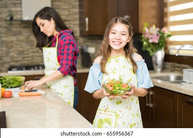 Portrait Of A Beautiful Hispanic Girl Holding A Bowl Of A Freshly Made Salad In The Kitchen And Smiling