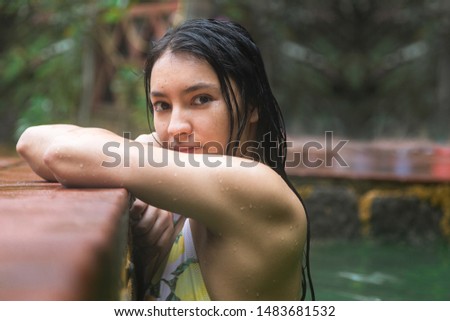 Portrait of beautiful Hispanic woman enjoying in natural hot springs - Latin woman at the edge of the natural spa pool - woman in swimsuit