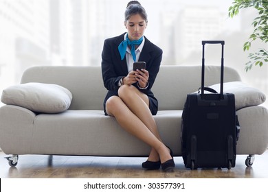 Portrait Of Beautiful Hostess In Airport With Mobile Phone.