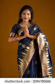 Portrait of a beautiful Indian girl in a greeting pose to Namaste hands. India woman in traditional saree.