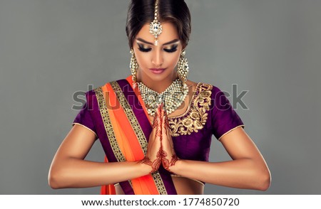 Portrait of a beautiful indian girl in a greetting pose to Namaste .India woman in traditional sari dress and jewelry.