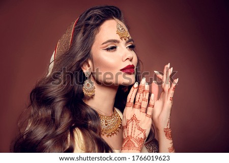 Portrait of beautiful indian girl in sari. Young hindu woman model with kundan golden jewelry set. Traditional Indian costume lehenga choli. Mehendi Henna painting on woman's hands.