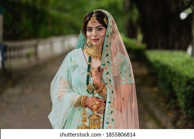 Portrait of beautiful Indian girl wearing wedding lehenga. Young Hindu woman model with tattoo mehndi and kundan jewelry . Traditional Indian wedding costume lehenga choli.