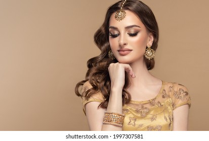 Portrait of beautiful indian girl. Young hindu woman model with golden kundan jewelry set, earrings, tikka and bracelet  . Traditional India costume lehenga choli or saree . Curly hair - Shutterstock ID 1997307581