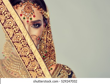 Portrait of beautiful indian girl. Young hindu woman model with golden kundan jewelry set . Traditional Indian costume lehenga choli .