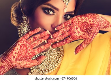 Portrait of beautiful indian girl. Young hindu woman model with tatoo mehndi  and kundan jewelry. Traditional Indian costume lehenga choli .