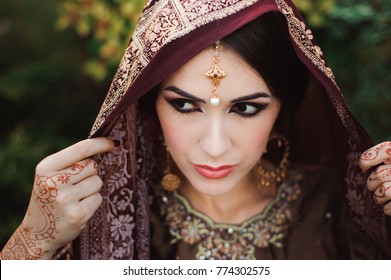 Portrait of beautiful indian girl . Young hindu woman model with tatoo mehndi and kundan jewelry.
