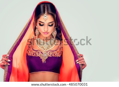 Portrait of beautiful indian girl . Young hindu woman model  with tatoo mehndi  and kundan jewelry . Traditional Indian costume lehenga choli .