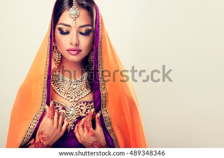Portrait of beautiful indian girl . Young hindu woman model  with tatoo mehndi  and kundan jewelry . Traditional Indian costume lehenga choli .
