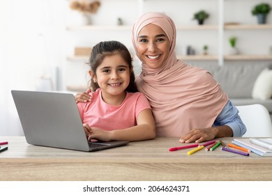 Portrait Of Beautiful Islamic Lady In Hijab And Her Little Daughter Sitting At Table With Laptop, Happy Middle Eastern Family Spending Time With Computer, Study Online Or Browsing Internet, Closeup