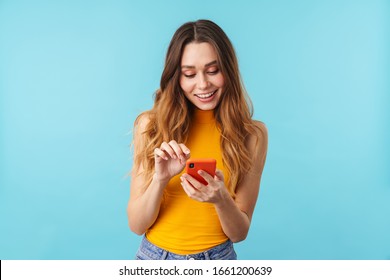 Portrait of beautiful joyous caucasian woman smiling and holding cellphone isolated over blue background in studio - Shutterstock ID 1661200639