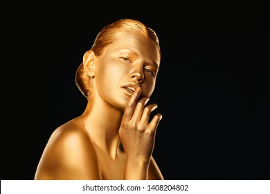 Portrait of beautiful lady with gold paint on skin against black background. Space for text