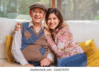Portrait of beautiful Latin woman hugging her older father smiling and looking at camera.