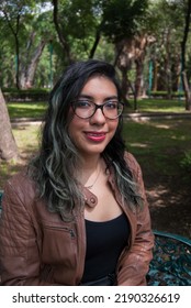 Portrait Of A Beautiful Latina Woman Sitting On A Bench In The Park