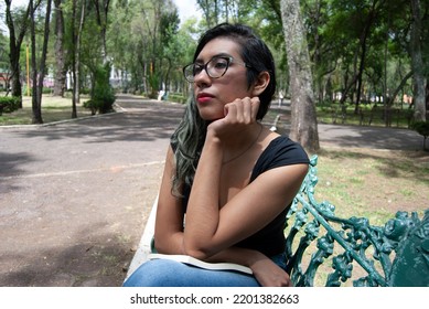 Portrait Of A Beautiful Latina Woman Sitting On A Bench In The Park