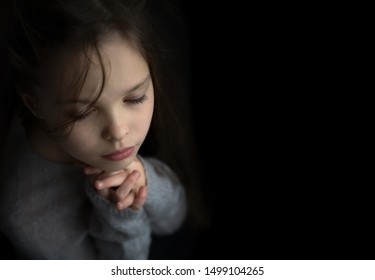 Portrait of a beautiful little baby girl praying. Facial expression. Kid and emotions. Faith and the Bible concept.
