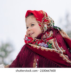 Portrait of beautiful little child girl during the walk in forest. She dressed in the old Russian style in red headscarf.