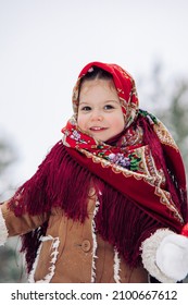 Portrait of beautiful little child girl during the walk in forest. She dressed in the old Russian style in red headscarf.