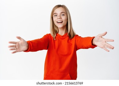 Portrait Of Beautiful Little Girl With Blond Hair, Smiling And Reaching For Hug, Stretching Arms To Cuddle, Receive Smth, Standing Over White Background