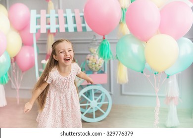A portrait of a beautiful little girl laughs in a studio decorated many color balloons