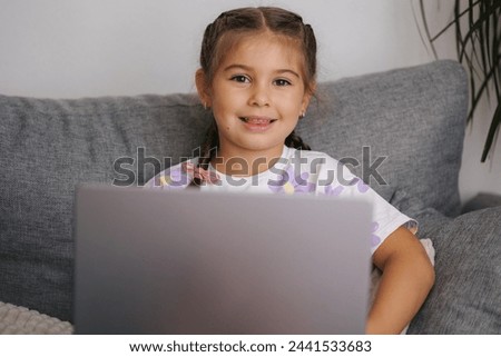 Portrait of beautiful little girl using smart devise. Five year old girl open and use laptop