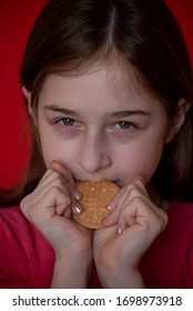 Portrait Of Beautiful, Lovely, L Child Girl, Bites Cookies On Red Background. Girl Eating Cookies. Girl 9 Years Old Portrait. The Concept Of Food And Man. Teenager